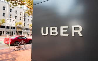 Sign with logo at the headquarters of car-sharing technology company Uber in the South of Market (SoMa) neighborhood of San Francisco, California, with red vehicle visible in the background parked on Market Street, October 13, 2017. SoMa is known for having one of the highest concentrations of technology companies and startups of any region worldwide. (Photo by Smith Collection/Gado/Getty Images)