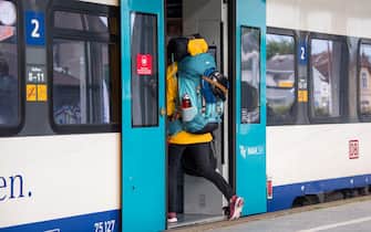 17 July 2022, Schleswig-Holstein, Westerland / Sylt: A woman with a backpack boards a regional train at the train station in the morning. Photo: Daniel Bockwoldt/dpa (Photo by Daniel Bockwoldt/picture alliance via Getty Images)
