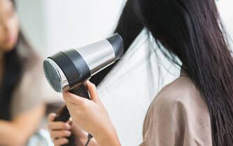 Woman with a hair dryer to heat the hair.