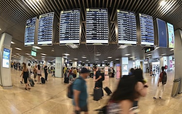 epa10091065 Passengers look at a departures screens at Adolfo Suarez Airport in Madrid, Spain, 25 July 2022, on first day of a planned four-day strike action to which Ryanair cabin crew are called for, this week.  EPA/FERNANDO VILLAR