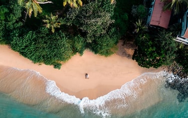 Loving couple on a secluded picturesque beach in tropical Sri Lanka surrounded by waves and palm trees