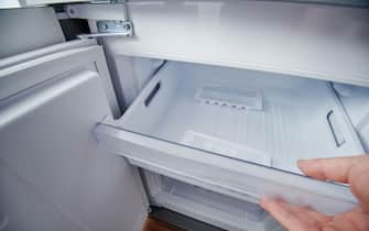 Open clean fridge freezer container with ice cubes