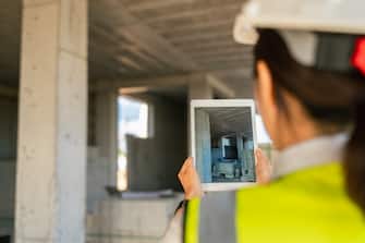 A female engineer is using a digital tablet on a construction site.