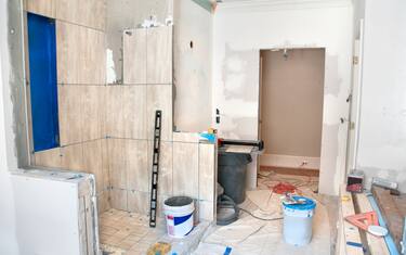 Master Bathroom Remodeling: Tiling in the Shower. The blue paint is a layer of anti-fracture / moisture membrane painted before the tiles are laid. The ground is protected by a piece of drop cloth.