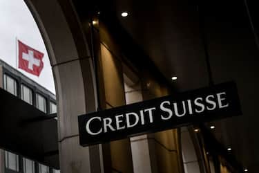 This photograph taken on May 6, 2022 shows a sign of Switzerland's second largest bank Credit Suisse on a branch's building next to a Swiss flag in downtown Geneva. (Photo by Fabrice COFFRINI / AFP) (Photo by FABRICE COFFRINI/AFP via Getty Images)