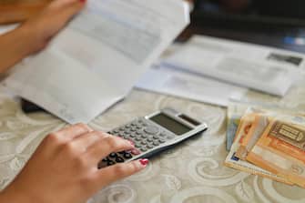 Una bolletta, una calcolatrice e soldi sul tavolo