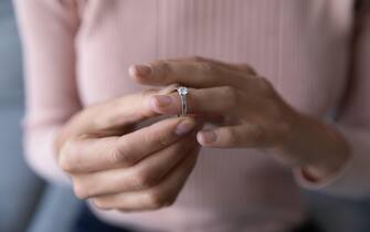 Close up woman taking off wedding ring, divorce concept