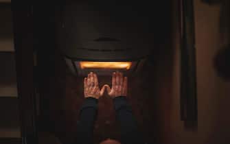 man's hands warming up on an electric stove.