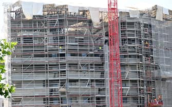 Operai edili al lavoro sulla faccaita di  un palazzo ricoperto da ponteggi, Milano, 14 giugno 2022. ANSA/DANIEL DAL ZENNARO