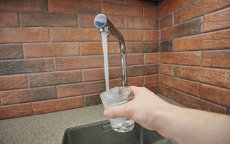 Pouring water in glass from faucet. Drinkable water theme