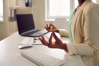Calm woman meditating and relaxing sitting at office desk during her working day