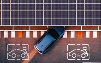 Directly above view taken with drone of a charging station for electric and hybrid cars using solar panels to generate electricity to charge cars battery while are parked in the city.