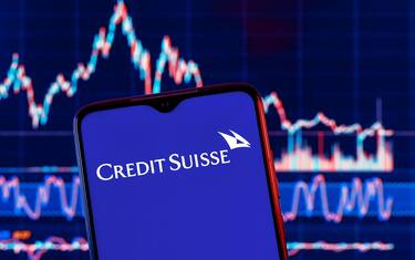 Smartphone with Credit Suisse bank logo. Credit Suisse stock chart on the background.