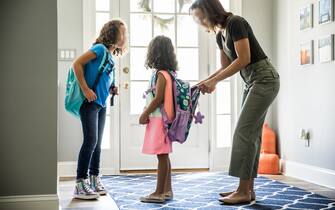 1273891151 Mother packing daughters backpacks for school