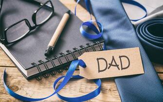 Father's day concept. Blue tie, text dad on the tag, office desk background