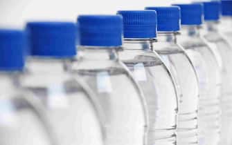 select focus on middle bottle in a row of plastic water bottles