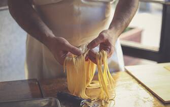 The Italian chef is splitting fettuccine Pasta.