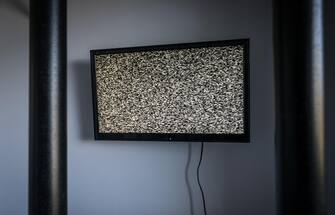 A TV on the wall of a prison cell behind bars