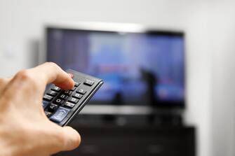 hand hold remote control in front of tv