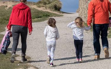 A family walking home along a footpath on The Headland in Newquay in Cornwall.