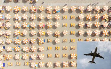 vista dall'alto di ombrelloni aperti in spiaggia e un aereo che decolla