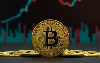 Uptrend of Bitcoin cryptocurrency shown by green and red candles. Coin of BTC in front of trading graph