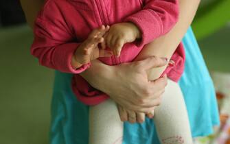 153438636 BERLIN, GERMANY - OCTOBER 05: Single mother Nancy Kett, 19, cradles her 11-month-old daughter Lucy in the playroom of the "Jule" facility for single parents in Marzahn-Hellersdorf district on October 5, 2012 in Berlin, Germany. The Jule project helps single parents by helping them to find jobs, job training and housing, advice on child development and day care in Marzahn-Hellersdorf, a district in east Berlin with high levels of unemployment and social problems. Currently 14 single mothers and one single father are participaring at Jule, which opened its doors in the spring of 2012. (Photo by Sean Gallup/Getty Images)