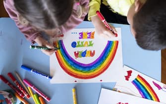 1212207041 MILAN, ITALY - MARCH 13: Children draw a rainbow and the slogan of hope being shared in Italy “Andrà tutto bene.” (Everything will be alright.) during quarantine measures amid the novel coronavirus COVID-19 pandemic on March 13, 2020 in Milan, Italy. Italy, which has seen the worst COVID-19 outbreak outside of China, tightened quarantine restrictions on Thursday, closing all commercial activities except supermarkets, pharmacies and banks. (Photo by Pietro D'Aprano/Getty Images)