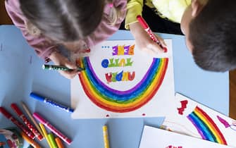 MILAN, ITALY - MARCH 13:  Children draw a rainbow and the slogan of hope being shared in Italy “Andrà tutto bene.” (Everything will be alright.) during quarantine measures amid the novel coronavirus COVID-19 pandemic on March 13, 2020 in Milan, Italy. Italy, which has seen the worst COVID-19 outbreak outside of China, tightened quarantine restrictions on Thursday, closing all commercial activities except supermarkets, pharmacies and banks.  (Photo by Pietro D'Aprano/Getty Images)