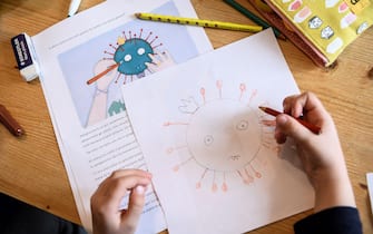 A child draws a COVID-19 coronavirus as part of school homeworks on March 12, 2020 in Manta, near Cuneo, Northwestern Italy, as Italy shut all stores except for pharmacies and food shops in a desperate bid to halt the spread of a coronavirus that has killed 827 in the the country in just over two weeks. (Photo by MARCO BERTORELLO / AFP) (Photo by MARCO BERTORELLO/AFP via Getty Images)