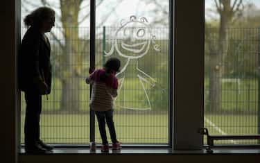 ALTRINCHAM, ENGLAND - APRIL 08:  A young girl paints a picture of herself on the school window as children of key workers take part in school activities at Oldfield Brow Primary School on April 08, 2020 in Altrincham, England. The government announced the closure of UK schools from March 20 except for the children of key workers, such as NHS staff, and vulnerable pupils, such as those looked after by local authorities. The prime minister has said schools will remain closed "until further notice," and many speculate they may not reopen until next term. (Photo by Christopher Furlong/Getty Images)