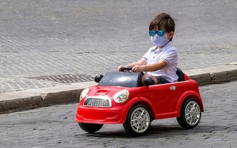 TOPSHOT - A boy wearing a face mask drives a toy car across Piazza Navona in Rome on May 28, 2020 as the country eases its lockdown aimed at curbing the spread of the COVID-19 infection, caused by the novel coronavirus. (Photo by Andreas SOLARO / AFP) (Photo by ANDREAS SOLARO/AFP via Getty Images)
