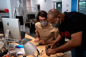 A photo taken on May 21, 2020 shows engineers, wearing a face mask, working on prototypes of a smart device called "iFeel-You", a bracelet used to maintain safe distance between people in daily life situations as well as on the beach, at the Italian Institute of Technology ((IIT)) in Genoa, Liguria, as the country eases its lockdown during the Phase 2 of deconfinment within the COVID-19 infection, caused by the novel coronavirus. - ITT is aiming to find a company able to produce the bracelet on an industrial scale at low price in a short time. (Photo by MARCO BERTORELLO / AFP) (Photo by MARCO BERTORELLO/AFP via Getty Images)