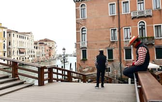 A Gondoliere checks his mobile phone as another waits for tourists in Venice on March 5, 2020. - Italy closed all schools and universities until March 15 to help combat the spread of the novel coronavirus crisis. The government decision was announced moments after health officials said the death toll from COVID-19 had jumped to 107 and the number of cases had passed 3,000. (Photo by ANDREA PATTARO / AFP) (Photo by ANDREA PATTARO/AFP via Getty Images)