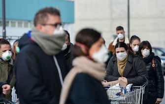Residents wearing respiratory mask wait to be given access to shop in a supermarket in small groups of forty people on February 23, 2020 in the small Italian town of Casalpusterlengo, under the shadow of a new coronavirus outbreak, as Italy took drastic containment steps as worldwide fears over the epidemic spiralled. (Photo by Miguel MEDINA / AFP) (Photo by MIGUEL MEDINA/AFP via Getty Images)
