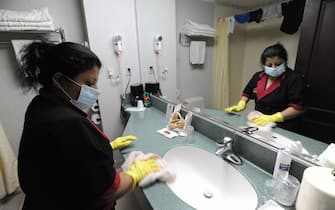 A cleaning woman wears a face mask while she cleans a bathroom at a hotel in San Salvador on May 4, 2009. El Salvador has confirmed its first two cases of swine flu, the country's health minister said Sunday as clinics and public hospitals to stepped up measures to combat the dreaded viral disease.  AFP PHOTO/ Jose CABEZAS (Photo credit should read Jose CABEZAS/AFP via Getty Images)