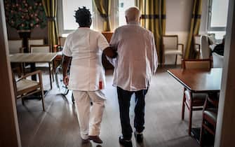 An elderly resident walks with the help of a nurse on July 5, 2018, in an establishment of accommodation for dependent elderly (EHPAD) in Paris. (Photo by STEPHANE DE SAKUTIN / AFP) (Photo by STEPHANE DE SAKUTIN/AFP via Getty Images)