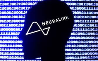 Neuralink logo displayed on a phone screen, a silhouette of a paper in shape of a human face and a binary code displayed on a screen are seen in this multiple exposure illustration photo taken in Krakow, Poland on December 10, 2021. (Photo by Jakub Porzycki/NurPhoto via Getty Images)