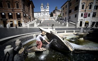 A tourist cools off at the Barcaccia fountain by the Spanish Steps in central Rome on August 01 2020 as Italy is in the grip of a heat wave. (Photo by Filippo MONTEFORTE / AFP) (Photo by FILIPPO MONTEFORTE/AFP via Getty Images)