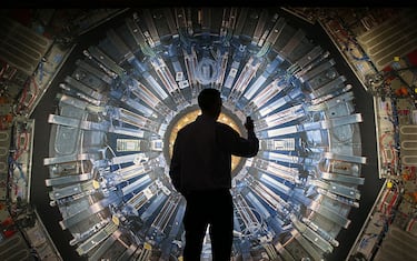 LONDON, ENGLAND - NOVEMBER 12:  A visitor takes a phone photograph of a large back lit image of the Large Hadron Collider (LHC) at the  Science Museum's 'Collider' exhibition on November 12, 2013 in London, England. At the exhibition, which opens to the public on November 13, 2013  visitors will see a theatre, video and sound art installation and artefacts from the LHC, providing a behind-the-scenes look at the CERN particle physics laboratory in Geneva. It touches on the discovery of the Higgs boson, or God particle, the realisation of scientist Peter Higgs theory.  (Photo by Peter Macdiarmid/Getty Images)