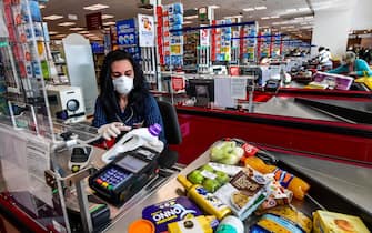 Italian cashier Valentina Pome works at an Esselunga supermarket in Milan's Famagosta district on April 30, 2020, during the country's lockdown aimed at curbing the spread of the COVID-19 infection, caused by the novel coronavirus. (Photo by Miguel MEDINA / AFP) (Photo by MIGUEL MEDINA/AFP via Getty Images)