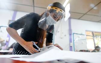 A woman works while wearing a mask and face shield at a tailor training centre, recently reopened with new plastic dividers to halt the spread of the COVID-19 coronavirus, in Yangon on June 9, 2020. (Photo by Ye Aung THU / AFP) (Photo by YE AUNG THU/AFP via Getty Images)