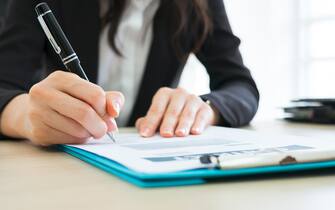 Business woman signing the contract to conclude a deal in modern office.