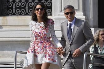 US actor George Clooney and his wife Amal Alamuddin leave the Aman Hotel on September 28, 2014 in Venice. Hollywood heartthrob George Clooney and Lebanese-British lawyer Amal Alamuddin married in Venice on Saturday September 27, 2014 before partying the night away with their A-list friends in one of the most high-profile celebrity weddings in years. "George Clooney and Amal Alamuddin were married today (September 27) in a private ceremony in Venice, Italy," Clooney spokesman Stan Rosenfield said. The announcement came as a surprise as the pair were not expected to officially tie the knot until Monday, though they are still tipped for a civil ceremony at the town hall to officialise the marriage under Italian law.   AFP PHOTO / ANDREAS SOLARO        (Photo credit should read ANDREAS SOLARO/AFP via Getty Images)