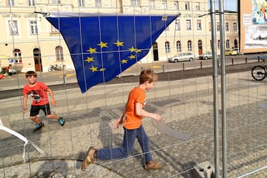 GORIZIA, ITALY - MAY 08:  Two children play near the flag of the European Union front of the wire mesh that divides Piazza Transalpina (Transalpina Square) on May 8, 2020 in Gorizia, Italy. Piazza Transalpina is a square divided between the municipalities of Gorizia in Italy and Nova Gorica in Slovenia. In 1947, the new border created between Italy and Yugoslavia was traced by dividing the square in two, crossed by the so-called "Muro di Gorizia". From May 1, 2004, with the entry of Slovenia into the European Union, the wall dividing the square was removed, but from March 11, 2020 the Slovenian government closed its borders with Italy to counter the spread of the coronavirus. A wire mesh has been positioned on the square to delimit the border between Italy and Slovenia, dividing many families, friends and couples.  (Photo by Pier Marco Tacca/Getty Images)