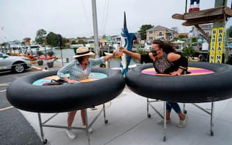 Restaurant guests try out social distancing devices made of rubber tubing as Fish Tails bar and grill opens for in person dining during the Coronavirus pandemic on May 29, 2020 in Ocean City, Maryland. - At 5pm today, restaurants and bars in the state of Maryland can open for outdoor and open air dining. (Photo by Alex Edelman / AFP) (Photo by ALEX EDELMAN/AFP via Getty Images)