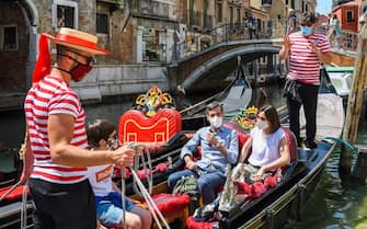 TOPSHOT - Gondoliers go with customers for a gondola ride on a canal in Venice on June 12, 2020 as the country eases its lockdown aimed at curbing the spread of the COVID-19 infection, caused by the novel coronavirus. (Photo by ANDREA PATTARO / AFP) (Photo by ANDREA PATTARO/AFP via Getty Images)