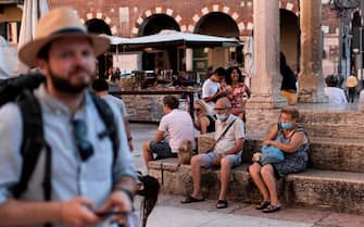 Tourists wearing protective face masks take a break in Piazza delle Erbe on July 25, 2020 in Verona, northern Italy. (Photo by MARCO BERTORELLO / AFP) (Photo by MARCO BERTORELLO/AFP via Getty Images)