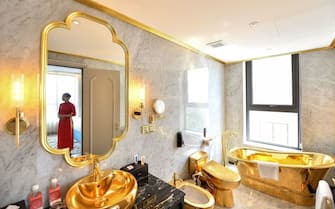 A staff member poses for a photograph inside the 1,000 USD per night executive two bedroom suite of the newly-inaugurated Dolce Hanoi Golden Lake hotel, the world's first gold-plated hotel, in Hanoi on July 2, 2020. (Photo by Manan VATSYAYANA / AFP) (Photo by MANAN VATSYAYANA/AFP via Getty Images)