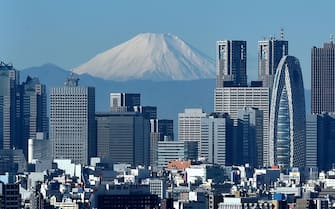 Japan's highest mountain, Mount Fuji (C) is seen behind the skyline of the Shinjuku area of Tokyo on December 6, 2014. Tokyo stocks closed at a seven-year high on December 5 -- extending their winning streak for a sixth straight day -- as a falling yen and oil prices continue to boost investor spirit.  AFP PHOTO / KAZUHIRO NOGI        (Photo credit should read KAZUHIRO NOGI/AFP via Getty Images)